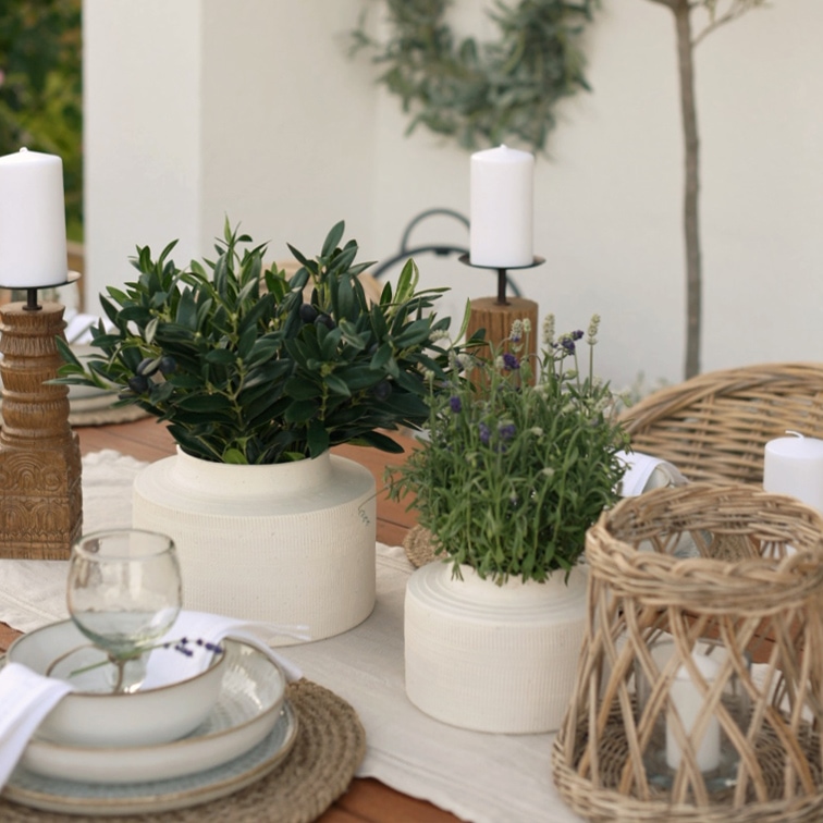 Witte keramische potten met groene planten op houten tafel met natuurlijke kandelaren