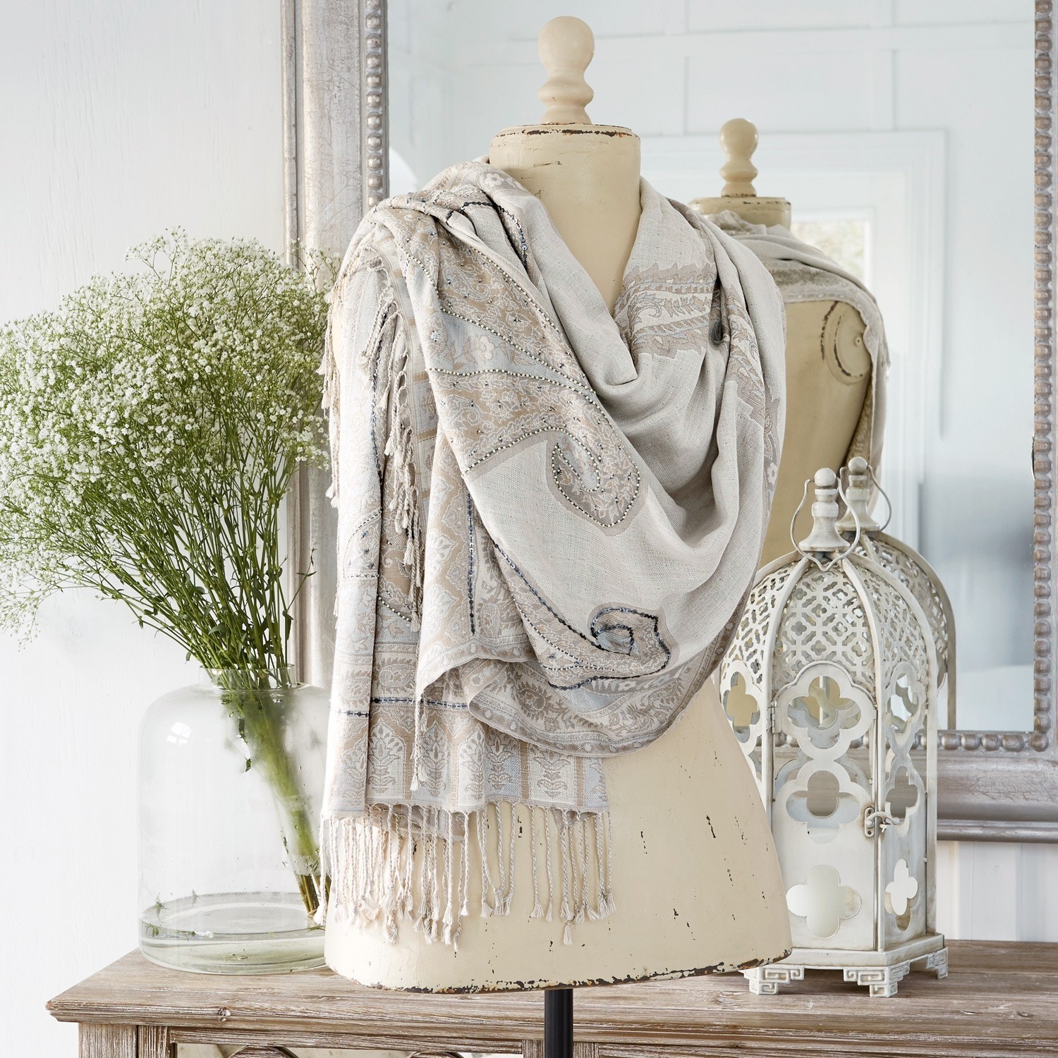 Sjaal Moyra Beige sjaal met paisley patroon en franjes op paspop, interieurdecoratie met lantaarn en bloemen