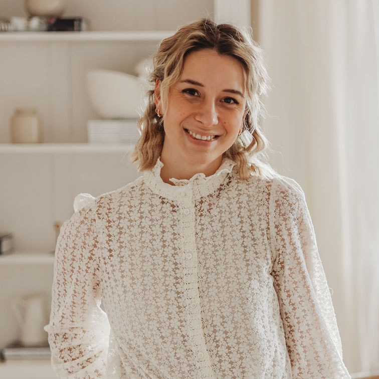 Vrouw in witte kanten blouse met bloemenpatroon in lichte woonruimte