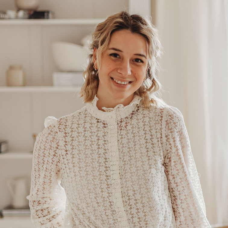 Vrouw in witte kanten blouse met bloemenpatroon in lichte woonruimte