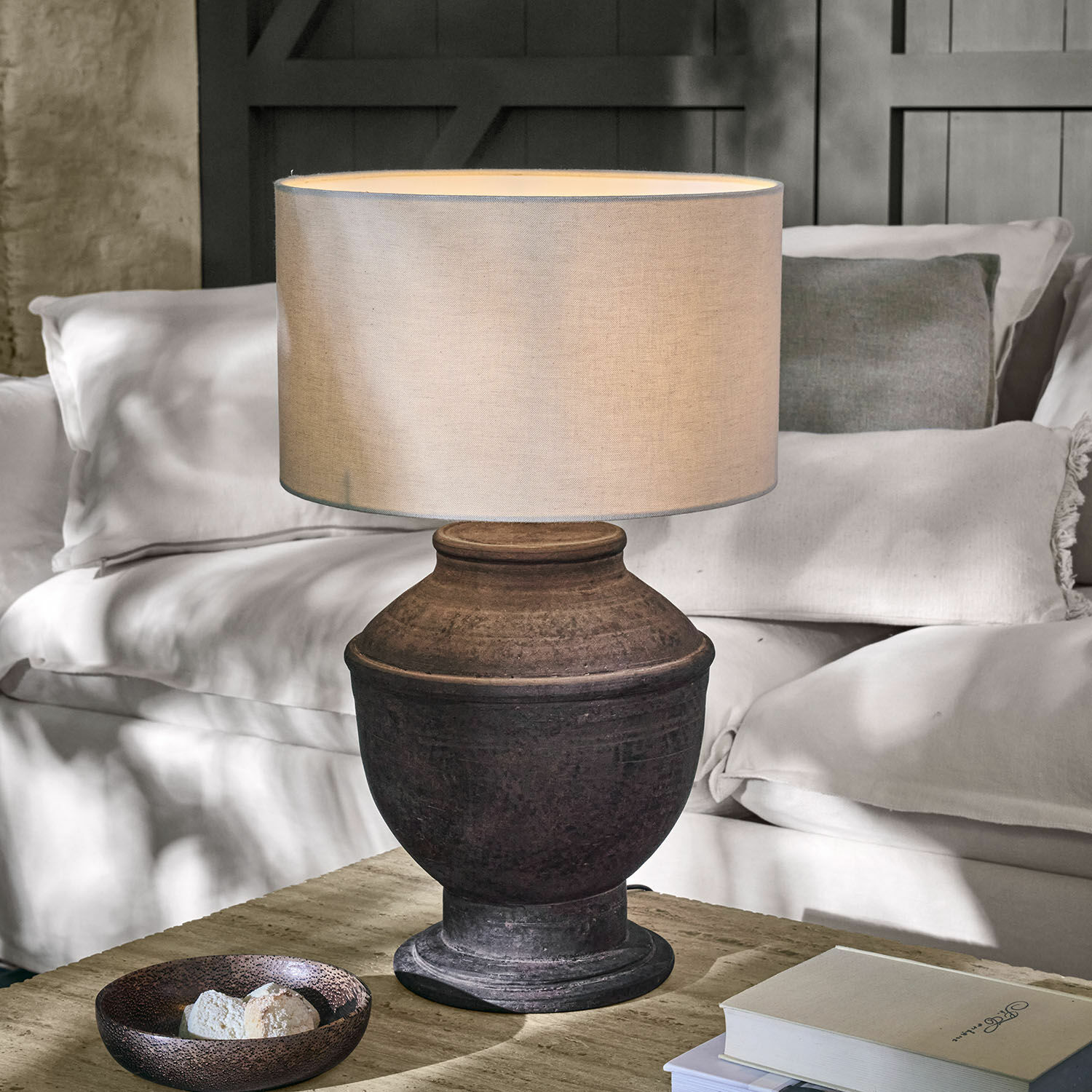 Tafellamp van donkere keramiek met beige kap op houten tafel in woonkamer