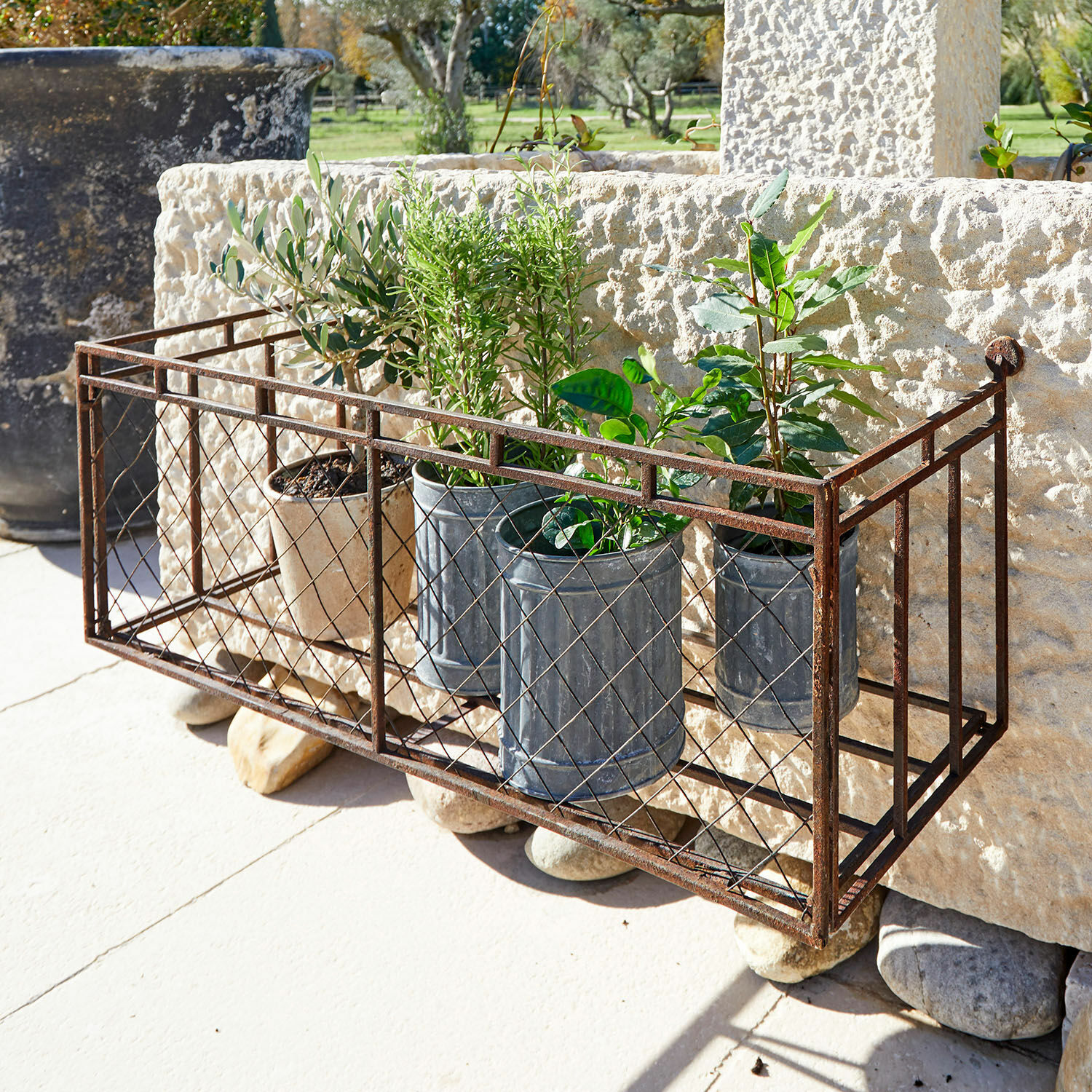 Plantenrek Edington Rustieke metalen plantenbak met roestkleur, potten en groene planten op terras