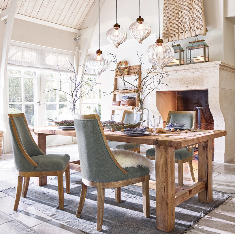 Eetkamer met massief houten tafel en grijze gestoffeerde stoelen, decoratieve glazen hanglampen