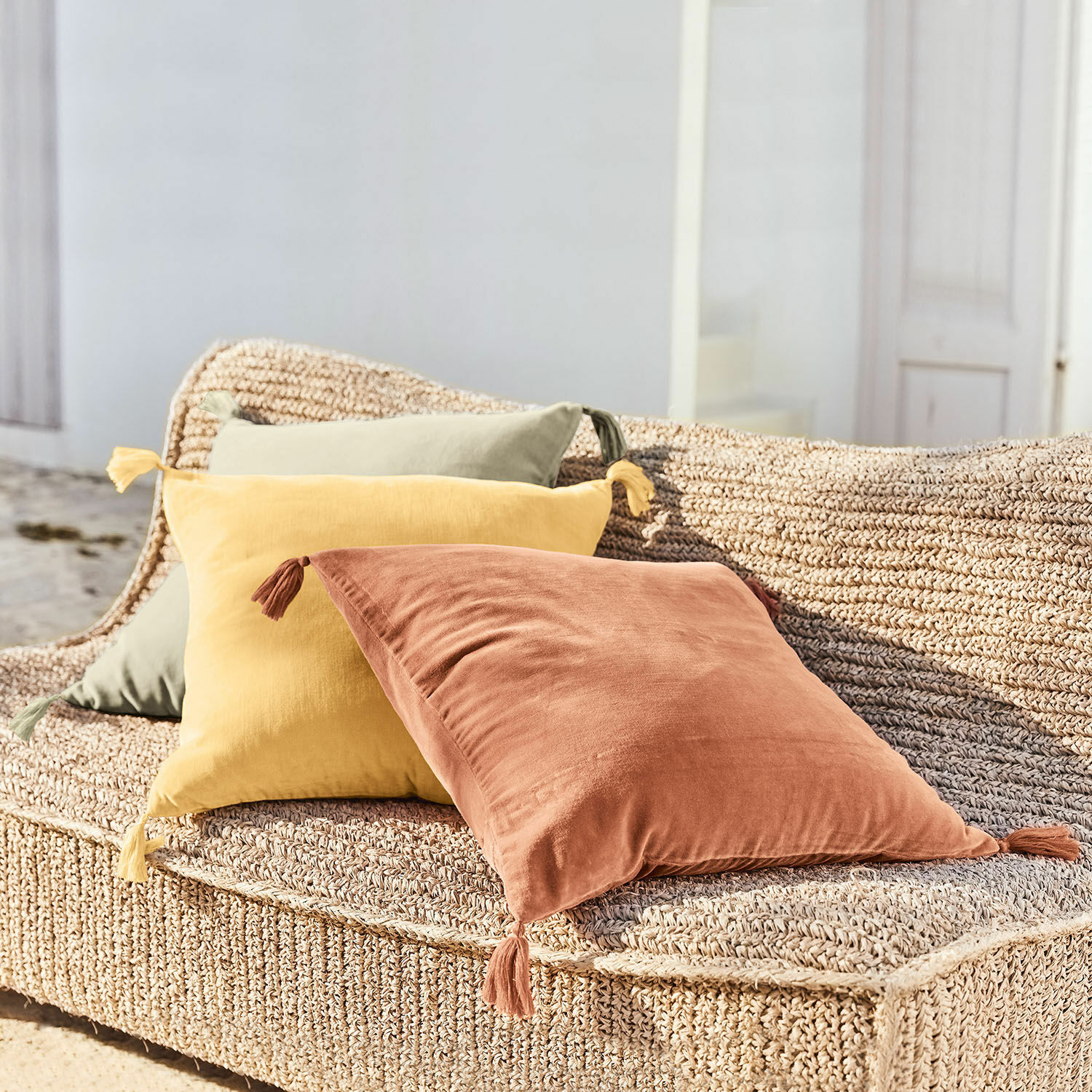Kussenhoes set van 3 Bedir Drie decoratieve katoenen kussens in terracotta, geel en groen op een gevlochten zitmeubel buiten
