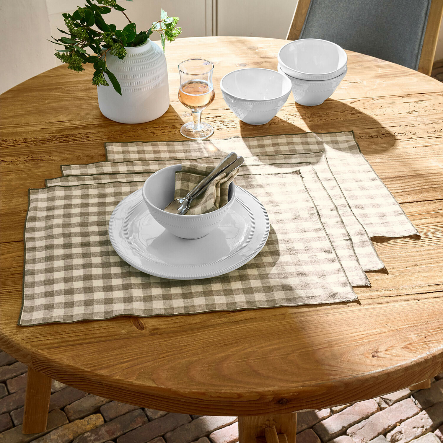 Placemat set van 4 Marrowby Witte keramische kommen en bord op houten tafel met beige-witte linnen placemats in ruitpatroon