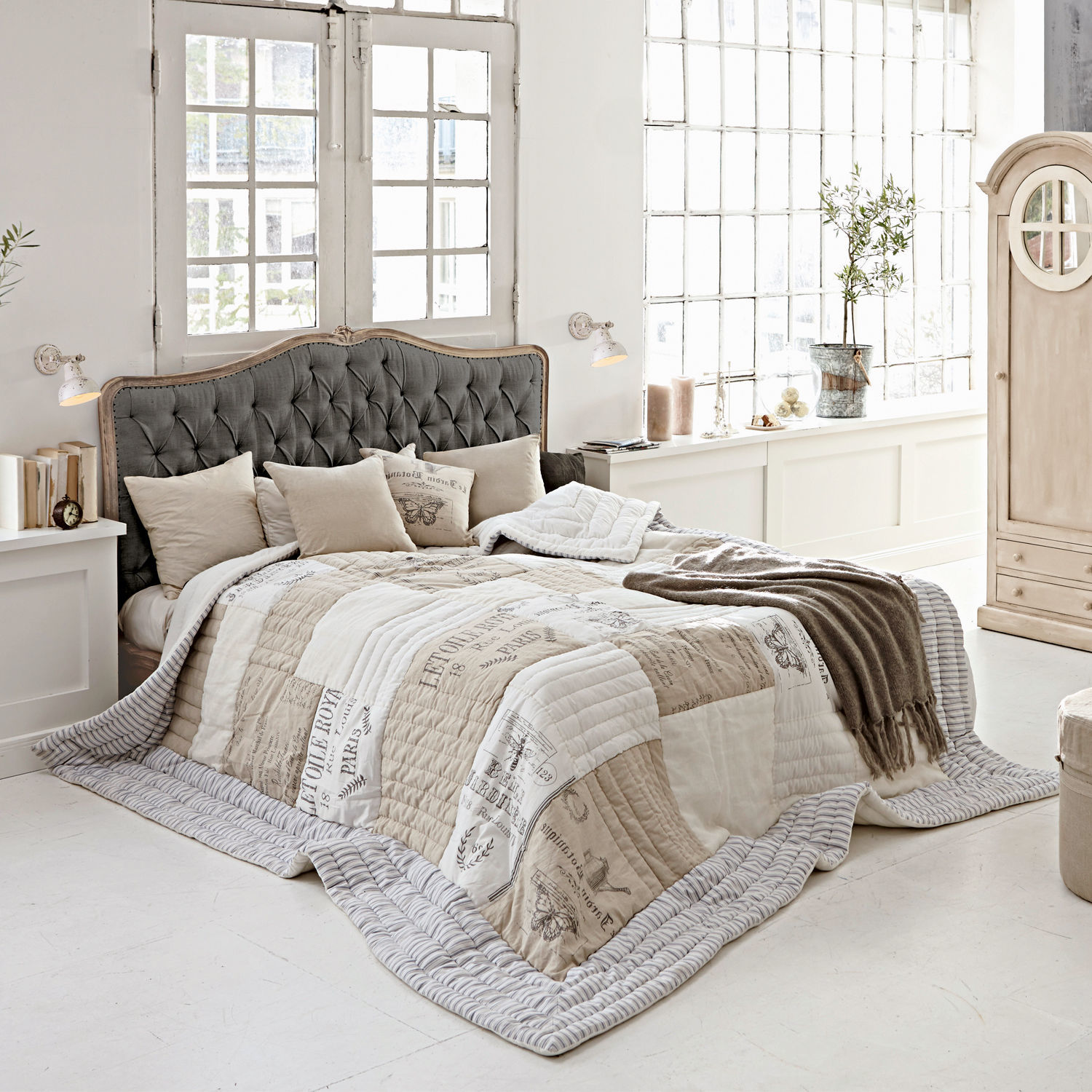 Bed Declaire Gezellige slaapkamer met bed met grijs gestoffeerd hoofdeinde en beige-witte vintage bedsprei