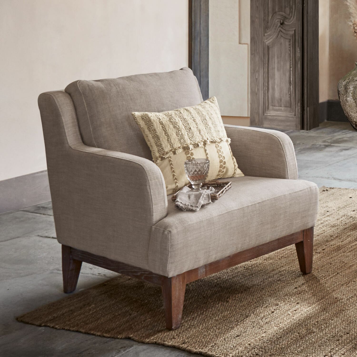 Fauteuil Saunders Beige stoffen fauteuil met houten poten op vloerkleed, stijlvolle woonkamermeubel