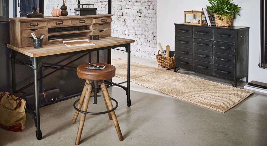 Bureau van hout en metaal met meerdere laden en een kruk met bruin leren zitting in industriële stijl