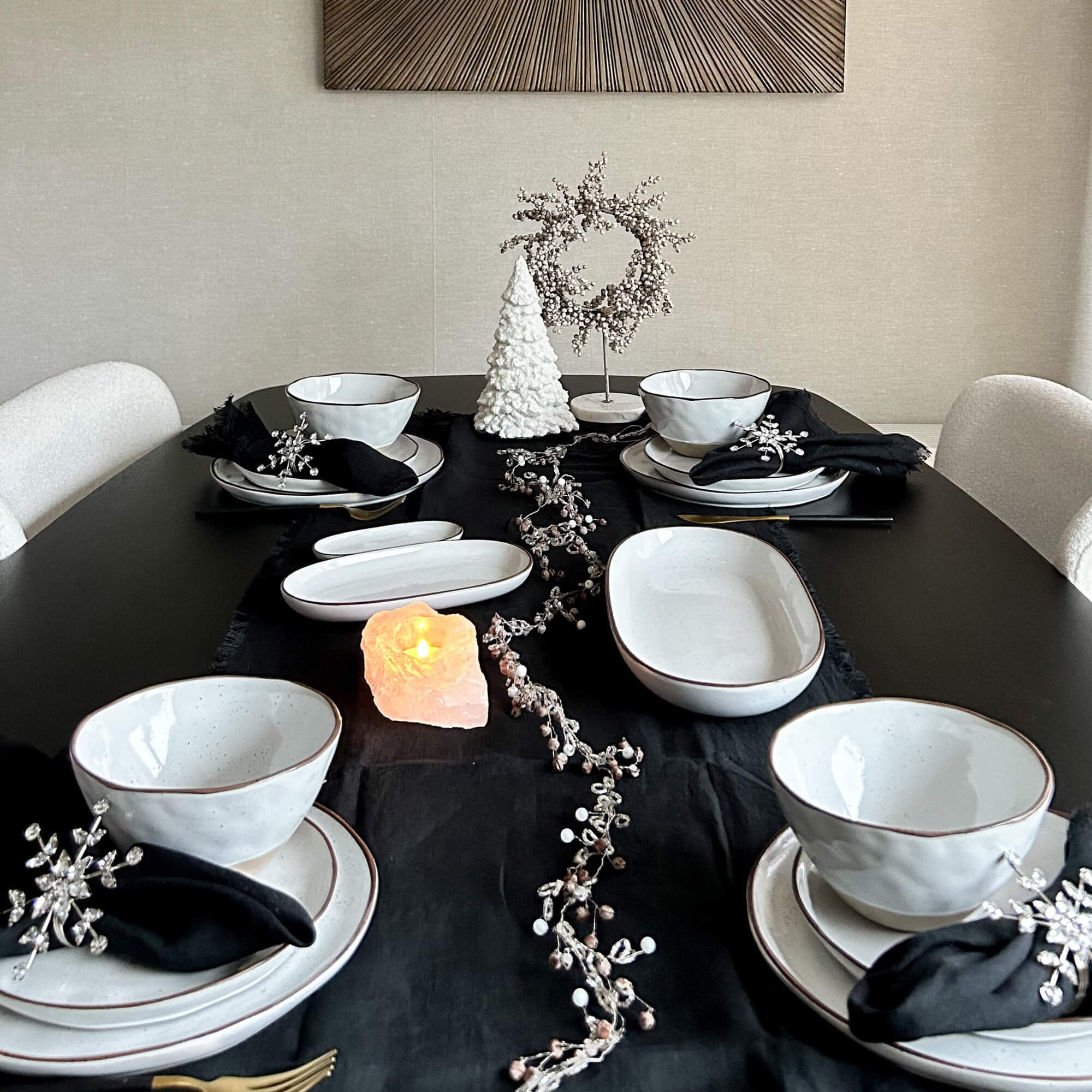 Witte keramische servies op zwarte tafelloper met kerstdecoratie en zoutkaars