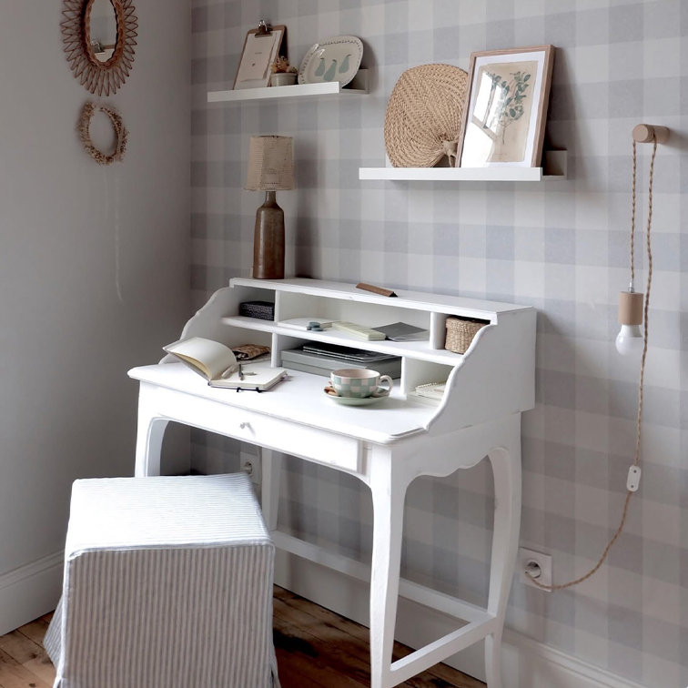 Witte houten secretaire met planken, lamp en kopje in gezellige kamer met geruit behang