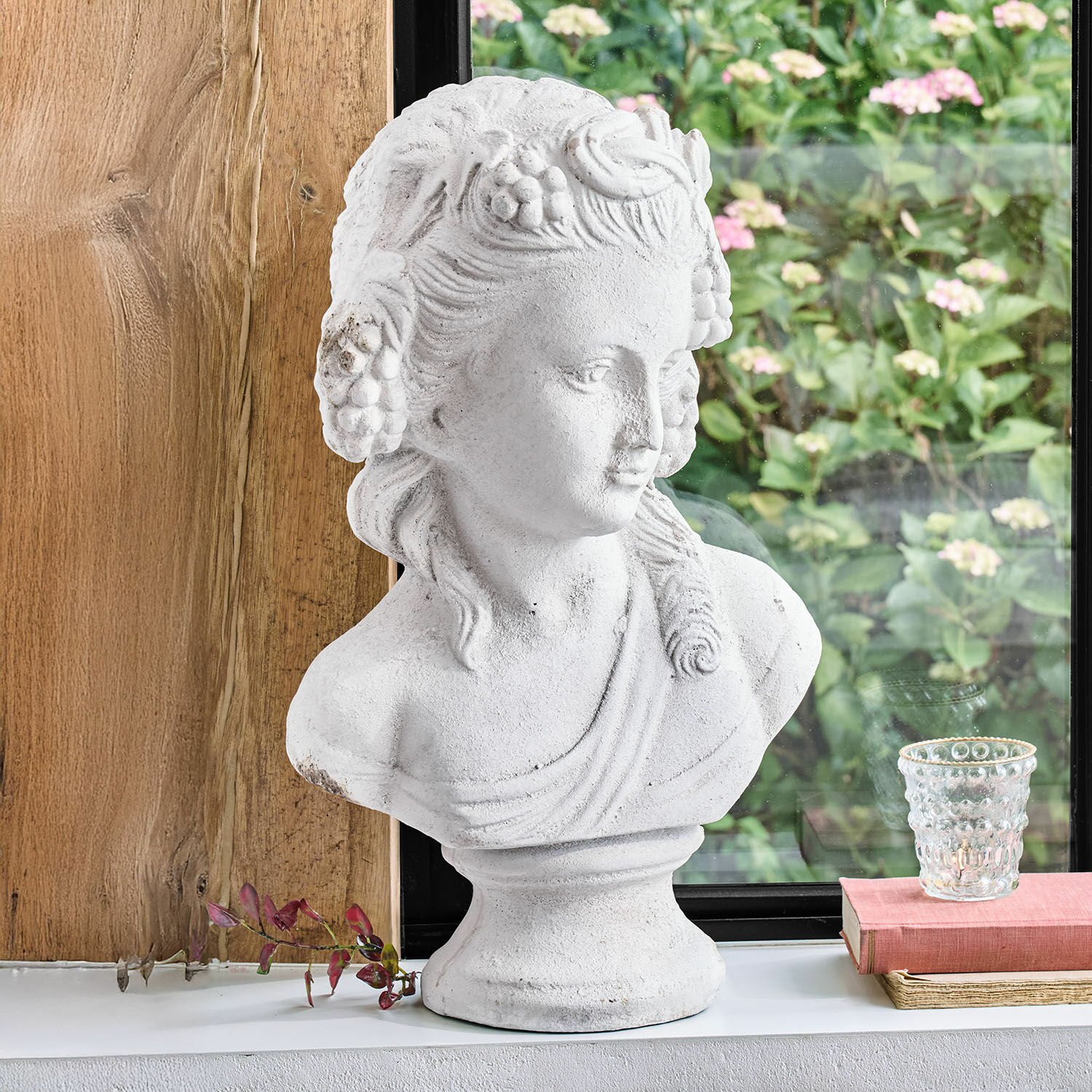 Witte decoratieve stenen vrouwenbuste met bloemmotieven op vensterbank geplaatst