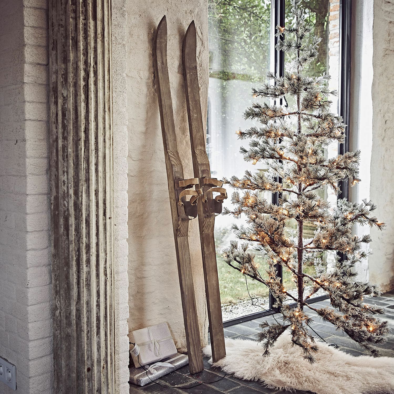 Decoratieve ski set van 2 Lambeth Vintage houten ski's naast verlichte kunstkerstboom op wit vloerkleed