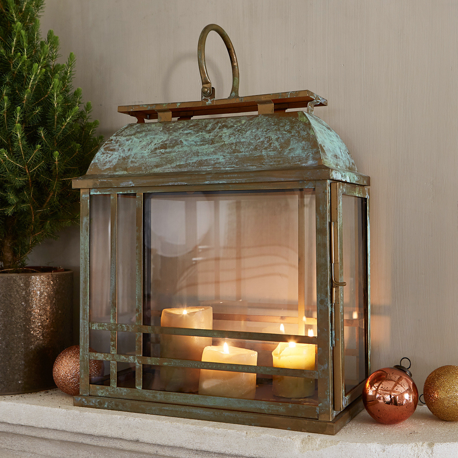 Metalen lantaarn met patina en glazen wanden met drie brandende decoratieve kaarsen