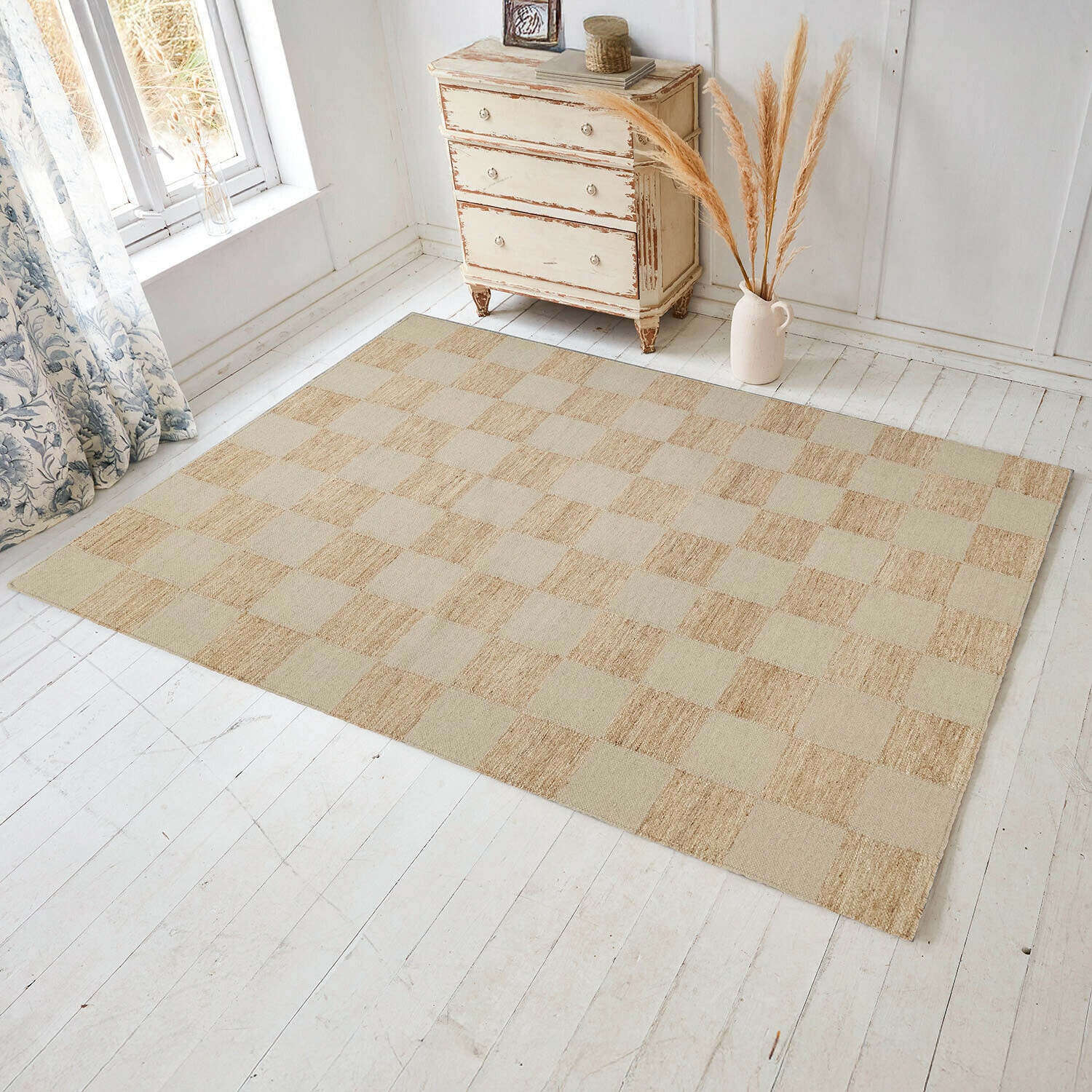 Vloerkleed Nexari Beige geruite vloerkleed van natuurlijk materiaal op lichte houten vloer in lichte kamer