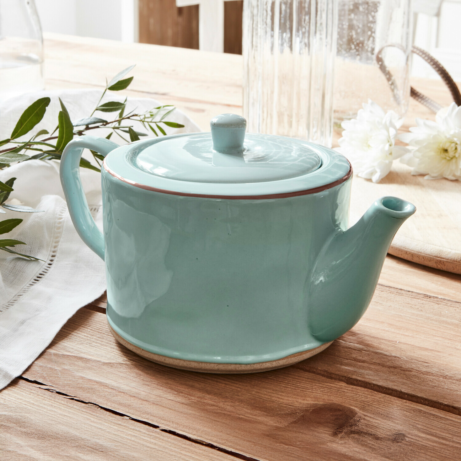 Theepot Biarré Groene keramische theepot met deksel op houten tafel met witte bloemen en groene bladeren