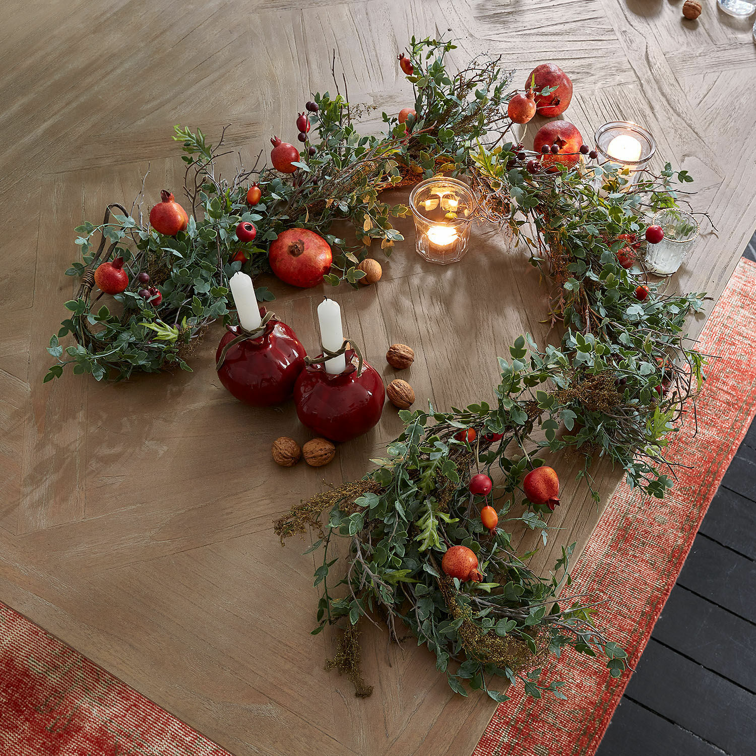 Guirlande Karidah Decoratieve krans van groene bladeren en rode vruchten op houten tafel met brandende kaarsen