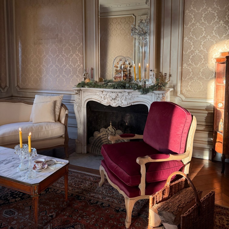 Klassieke woonkamer met bordeauxrode houten fauteuil en marmeren tafel met brandende kaarsen
