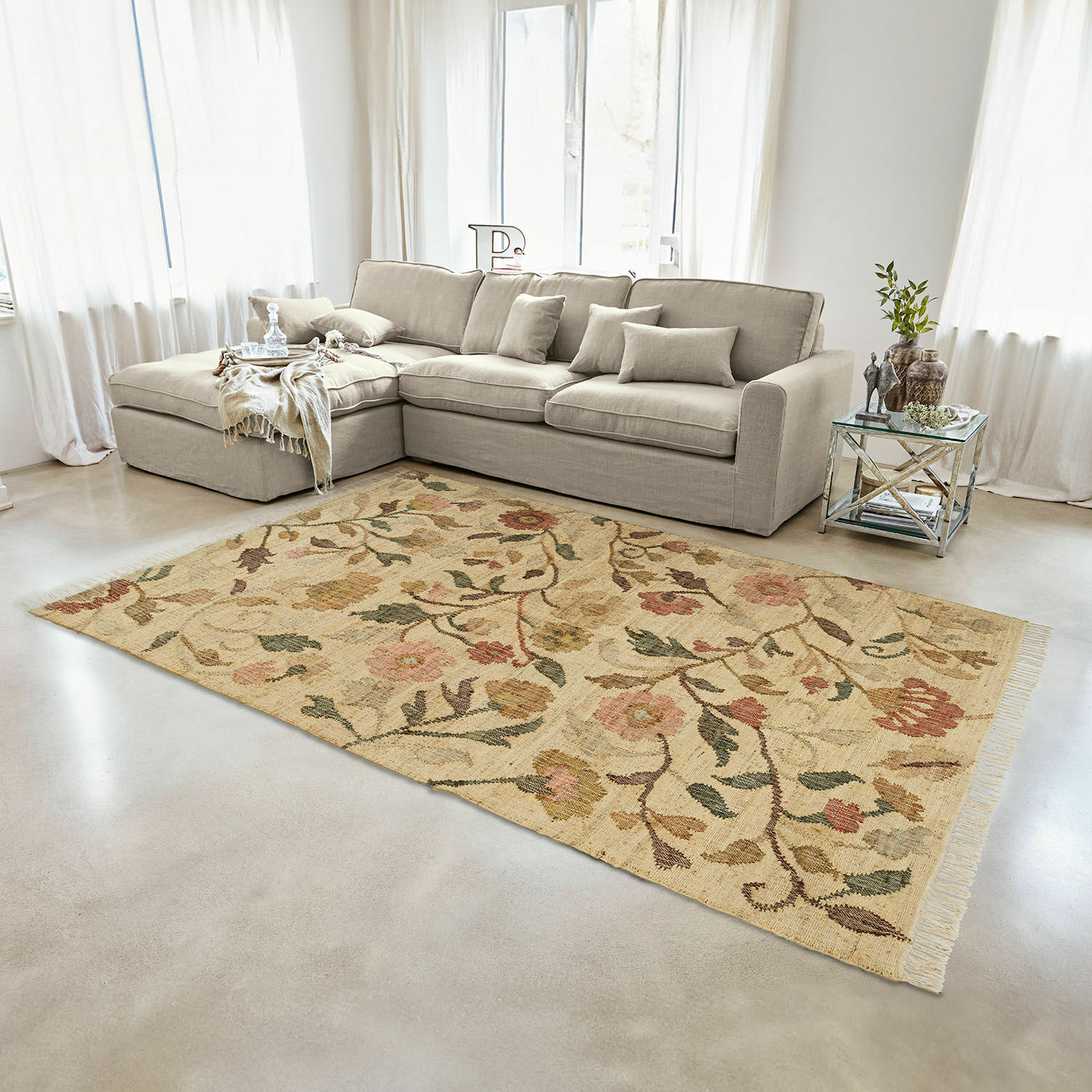 Beige wollen vloerkleed met bloemmotief in woonkamer met grijze bank en glazen bijzettafel