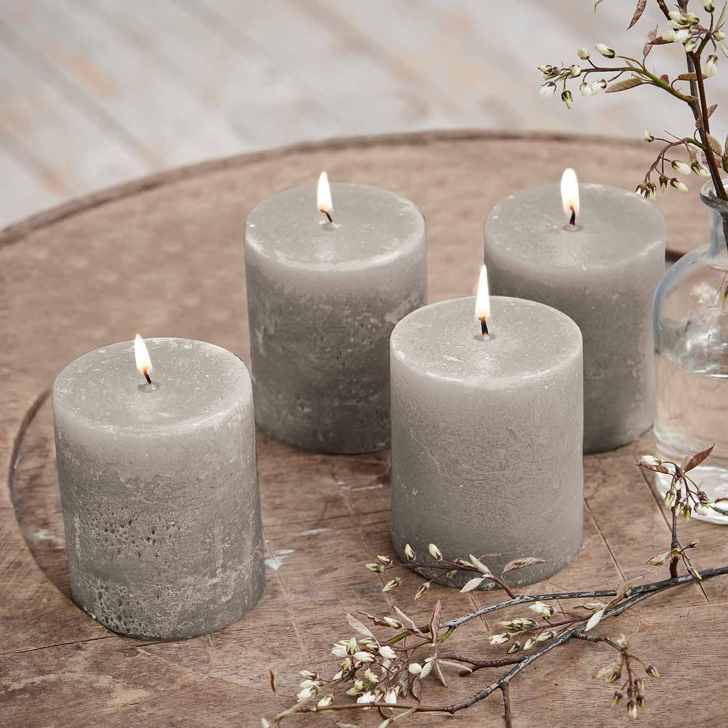 Set van vier grijze waskaarsen op houten tafel met bloemendecoratie, woondecoratie