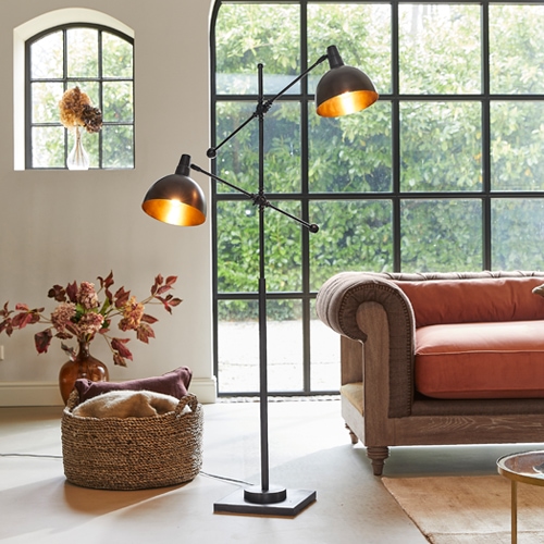 Zwarte metalen vloerlamp met twee verstelbare kappen in moderne woonkamer met oranje bank