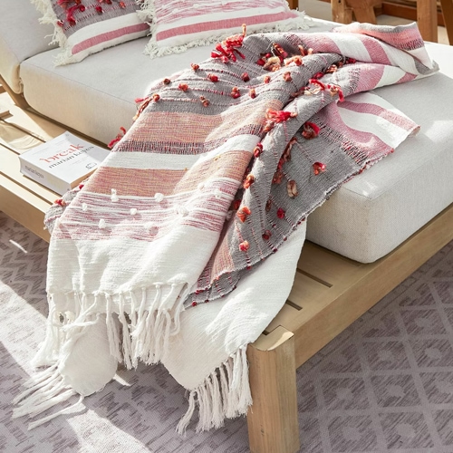 Decoratieve katoenen plaid in wit, roze en grijs met franjes en pompons, perfect voor de woonkamer