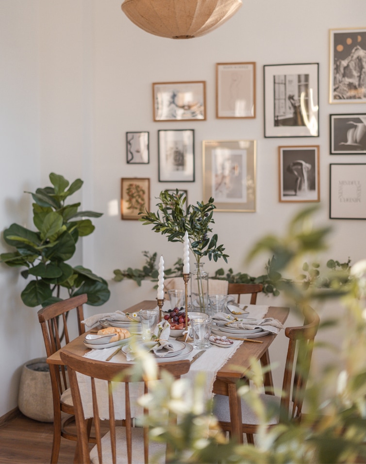 Eetkamer met houten tafel en stoelen, groene decoraties en kaarsen, natuurlijke interieurstijl