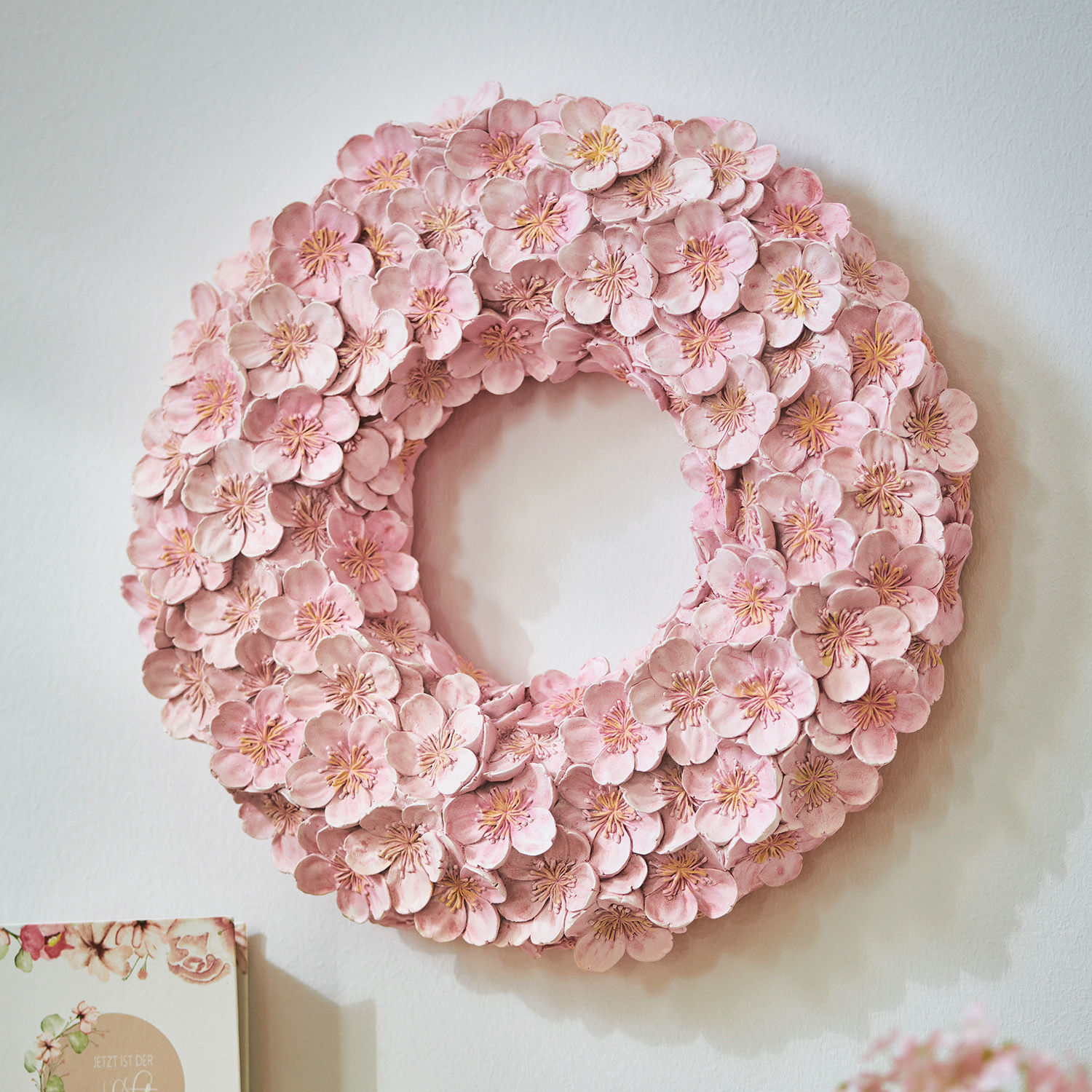 Decoratieve wandkrans van roze stoffen bloemen, stijlvolle woondecoratie.