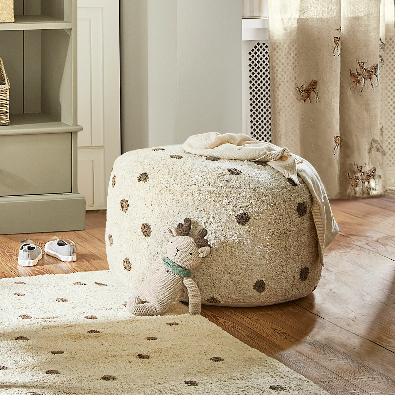 Poef Thivalie Beige zachte poef met stippen op houten vloer met knuffel en bijpassend vloerkleed