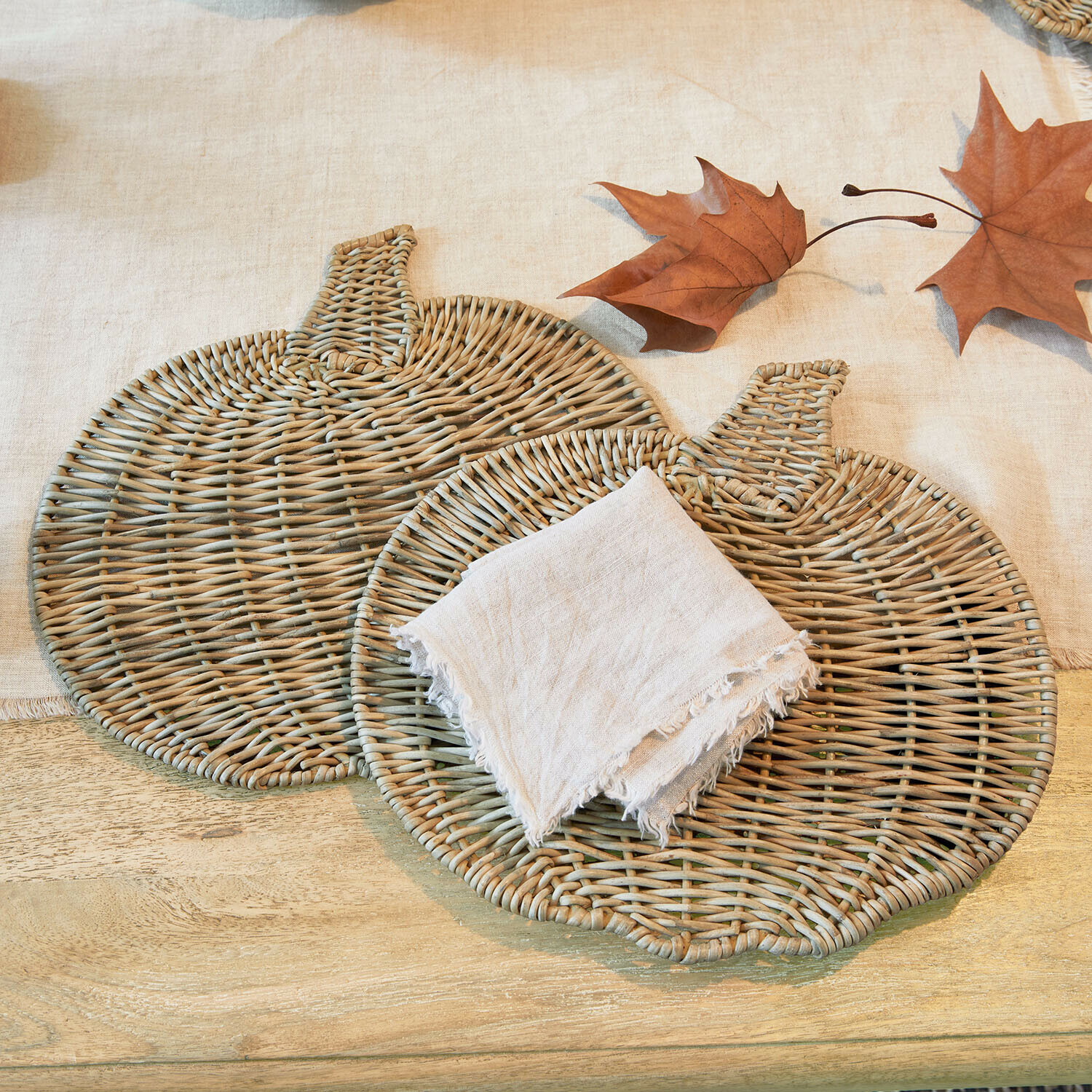 Placemat set van 2 Larivonne Twee natuurlijke pompoenvormige rieten placemats met linnen servet en herfstbladeren