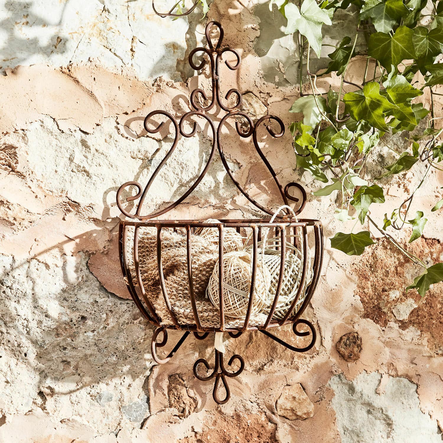 Siermand Marciac Rustieke metalen wandmand in roestkleur met decoratieve krullen en beige garenbollen