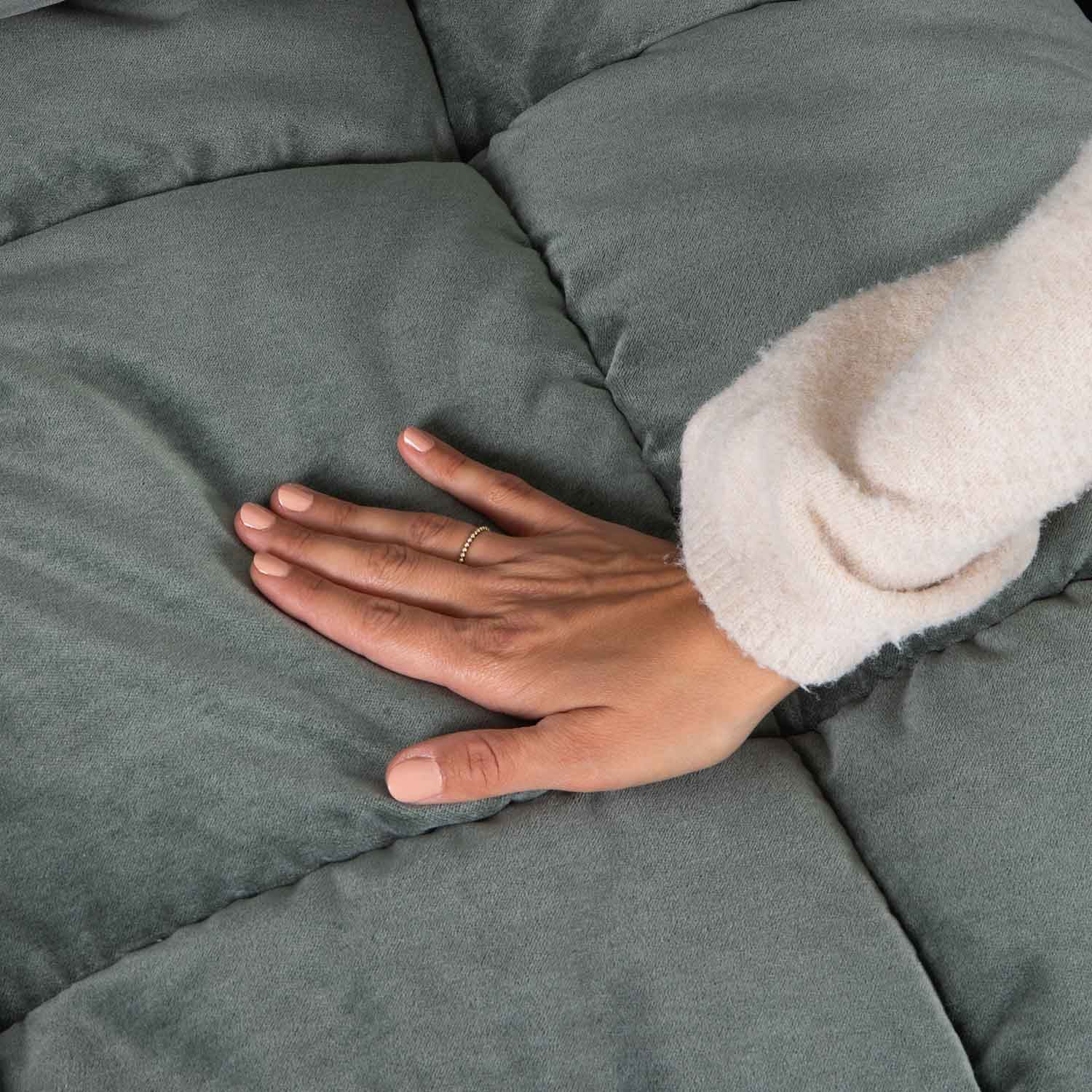 Hand op zacht, groen doorgestikt textiel, benadrukt comfort en kwaliteit van de stof