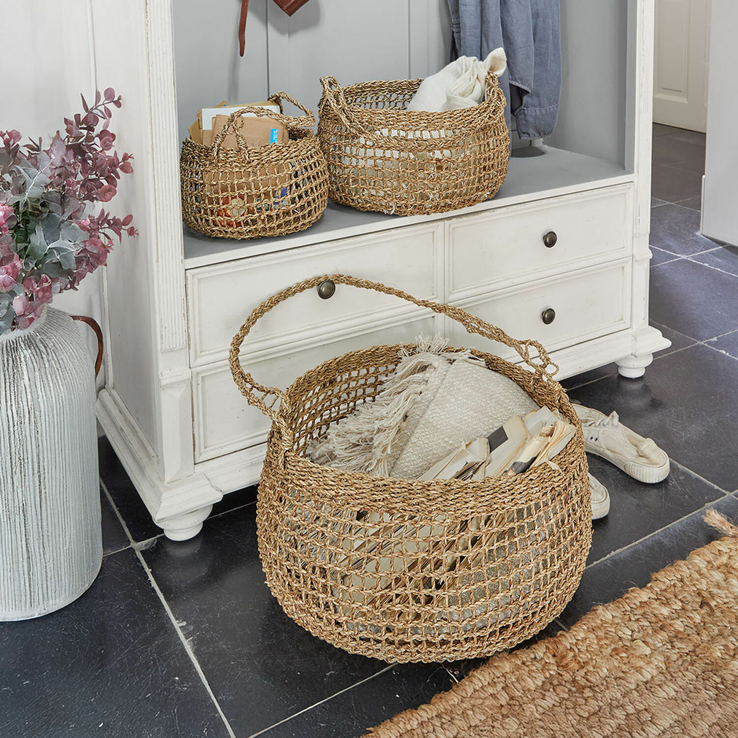 Drie natuurlijke rieten manden voor opslag in lichte kast op zwarte vloer