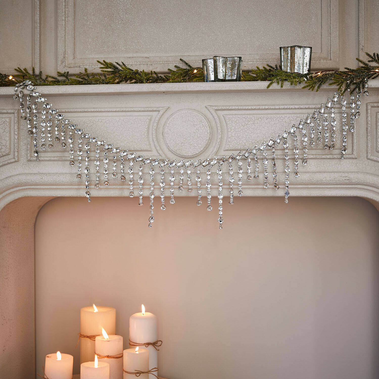 Decoratieve kristalketting aan schoorsteen met groene takken en brandende kaarsen, feestelijke decoratie