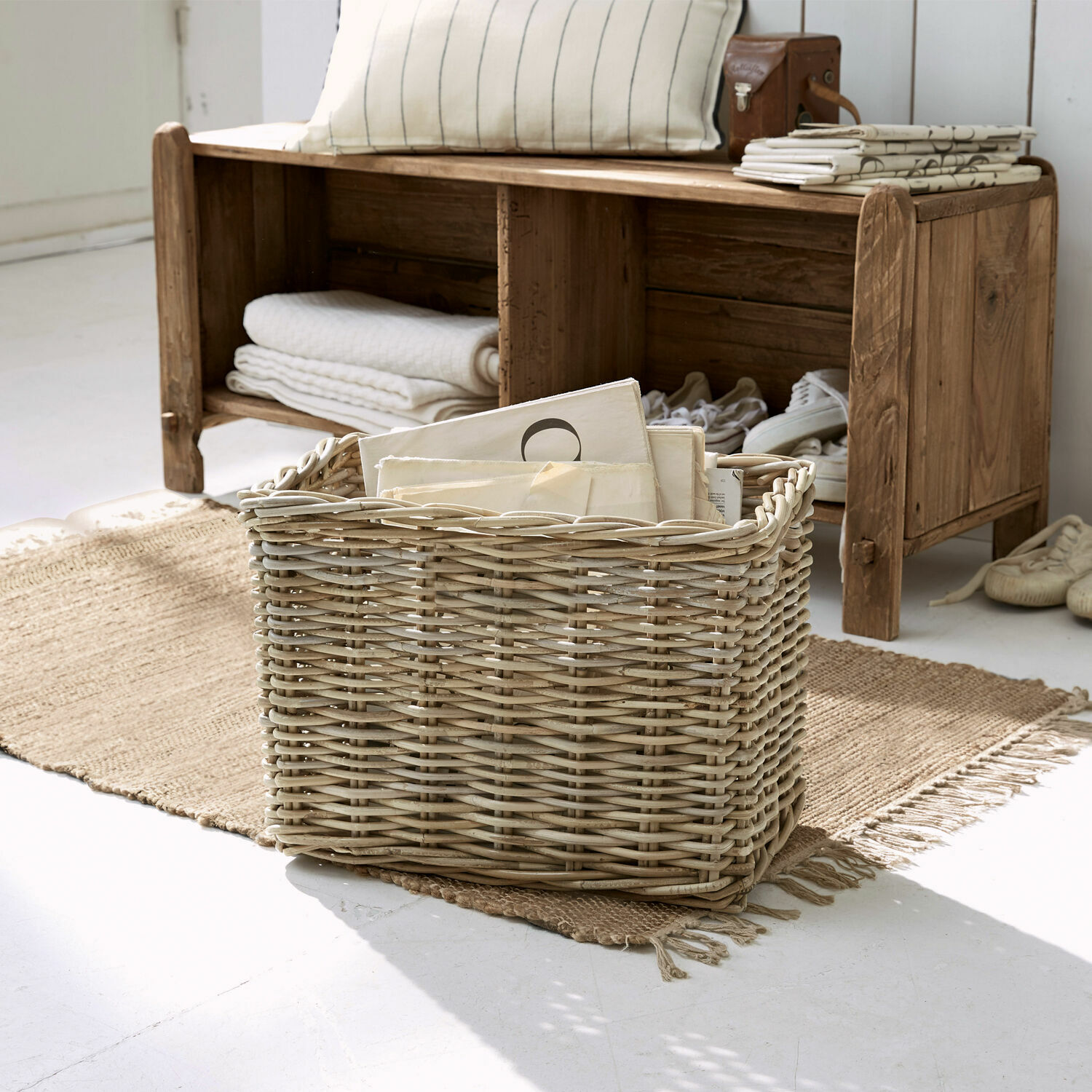 Natuurlijke rieten mand met documenten op jute vloerkleed in lichte kamer
