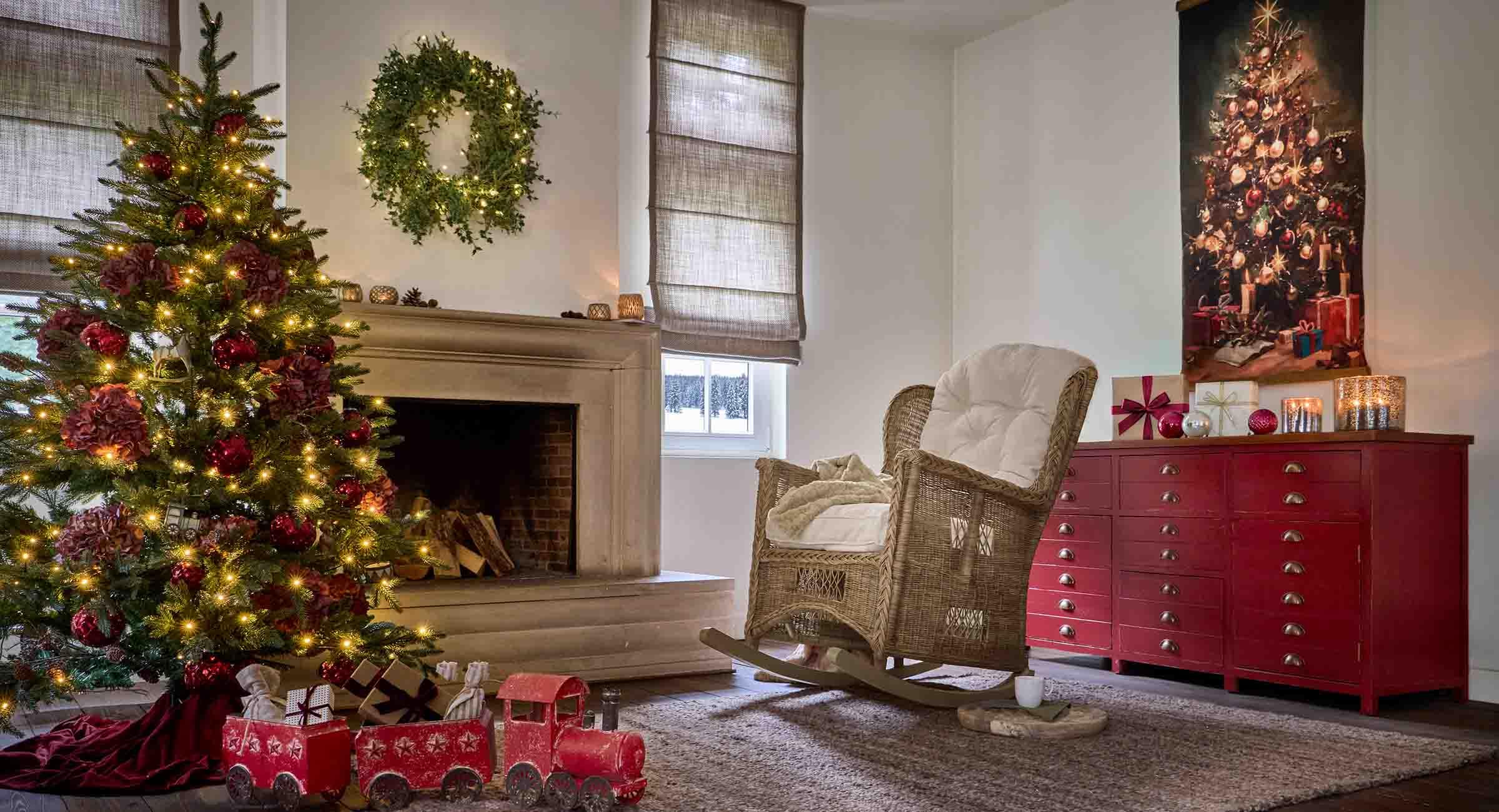 Gezellige woonkamer met kerstboom, rotan schommelstoel en rode kast met feestelijke decoratie