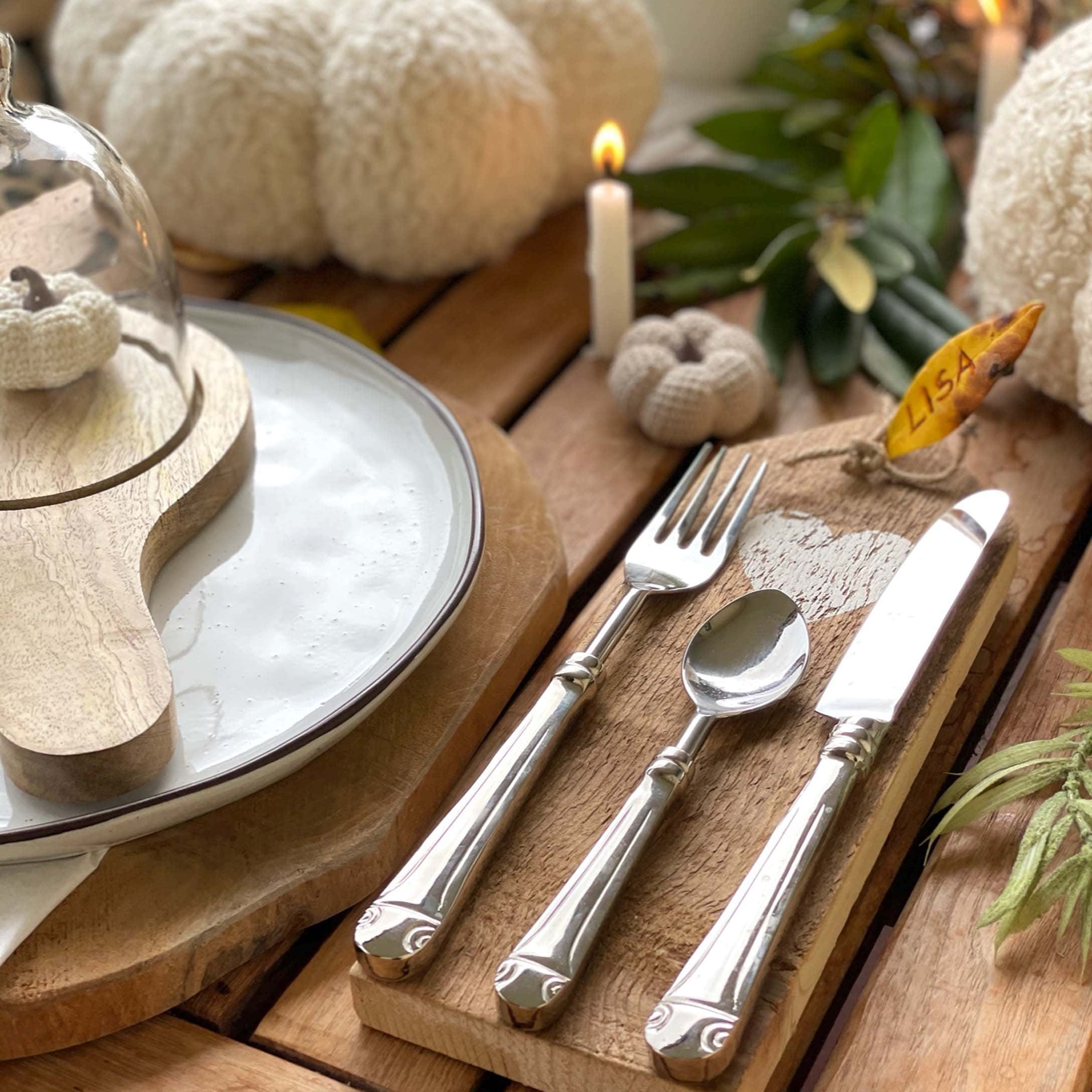 Rustieke houten tafel met herfstdecoratie, metalen bestek en witte gehaakte pompoenen