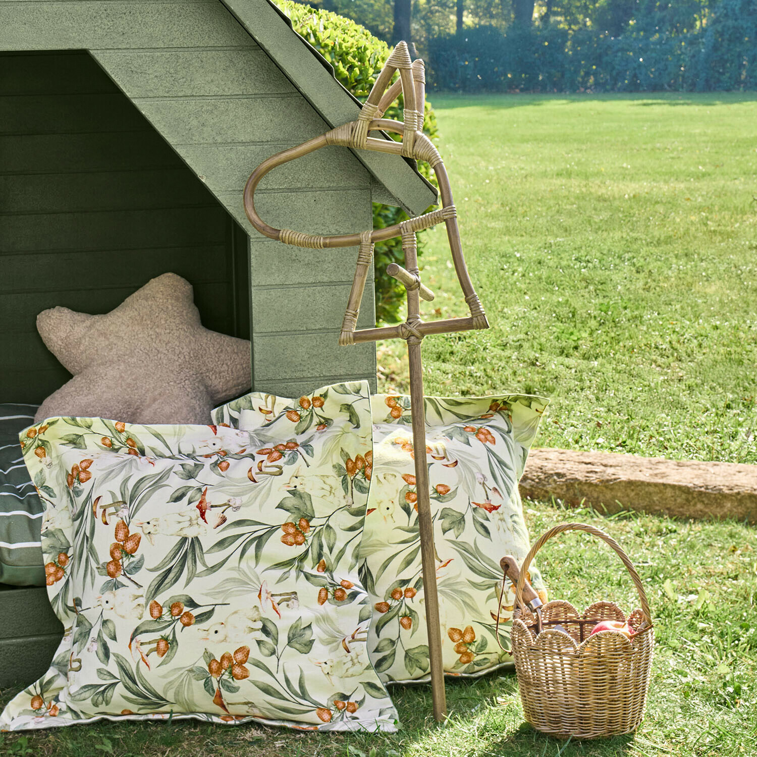 Decoratieve rieten stok in paardenvorm met bloemenkussens en een rieten mand op het gras