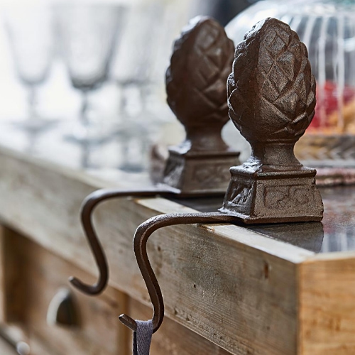 Bruine decoratieve ijzeren haken met dennenappelmotief op houten werkblad