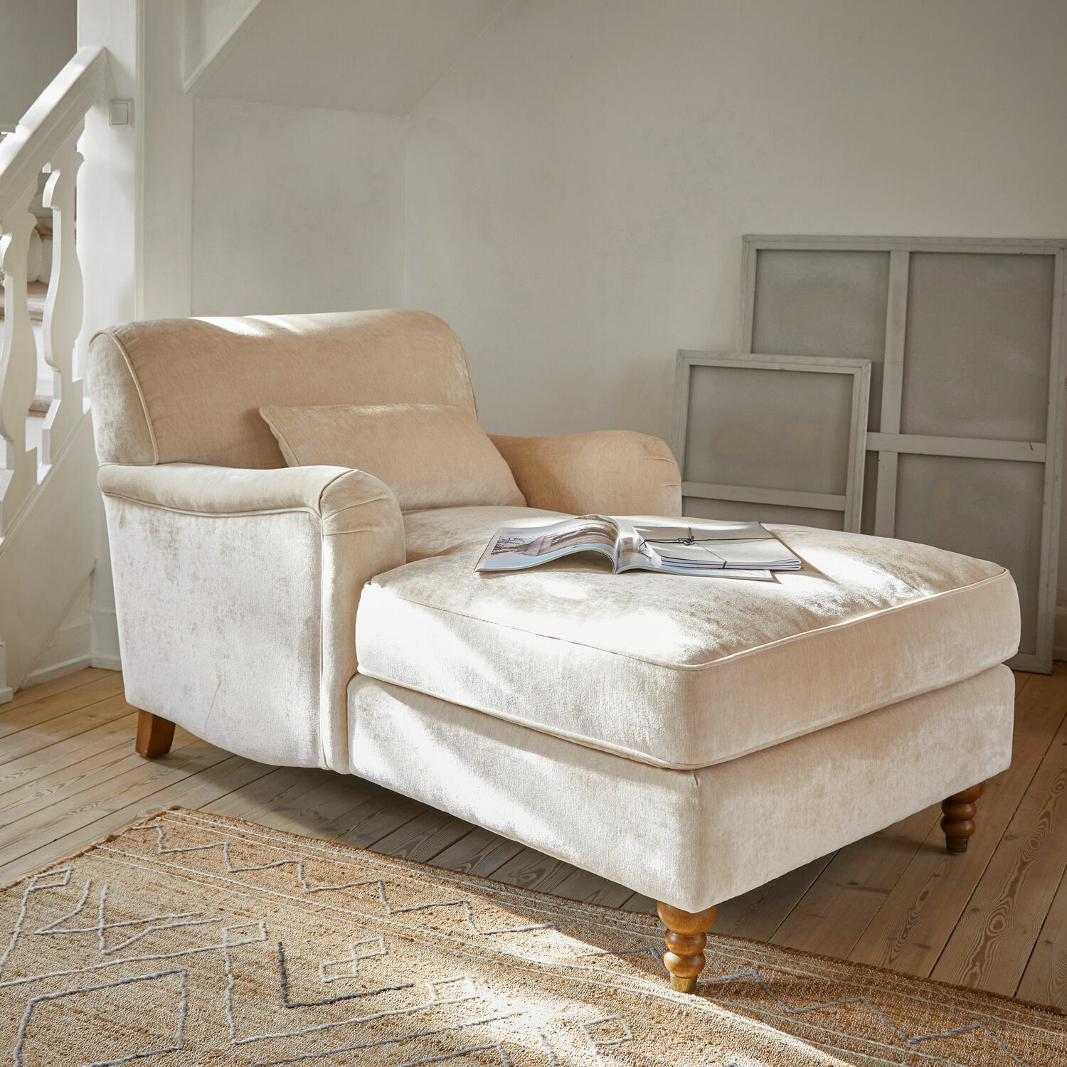 Beige fauteuil van zachte stof met voetensteun en houten poten in lichte woonkamer