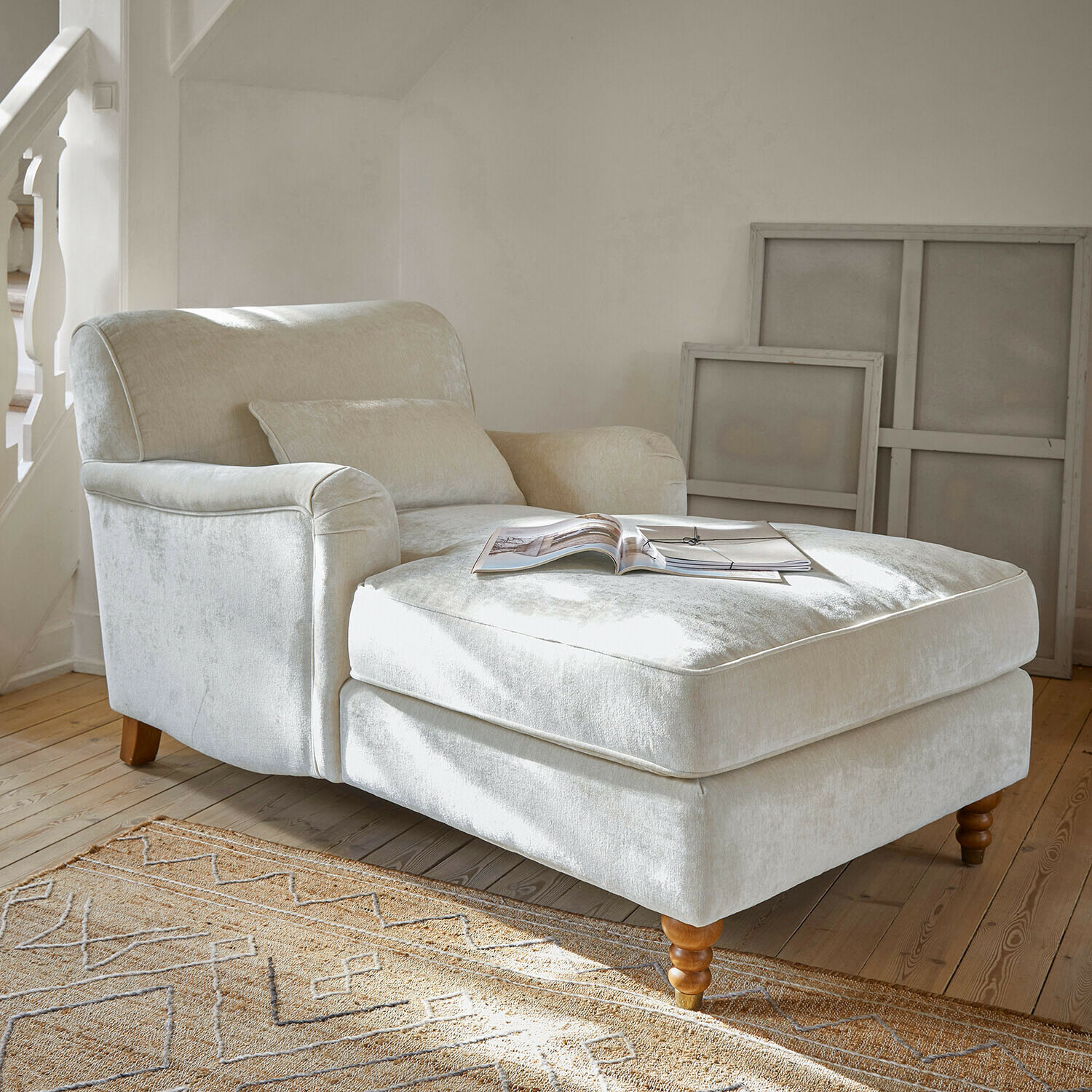 Beige fauteuil van zachte stof met voetensteun en houten poten in lichte woonkamer