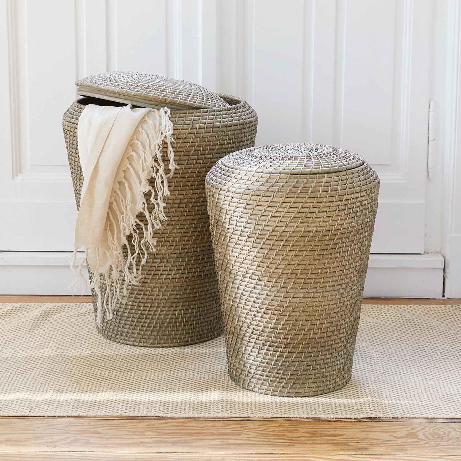 Wasmand, set van 2 Nora Twee beige rotan manden met deksels op een vloerkleed, praktische opbergers voor thuis