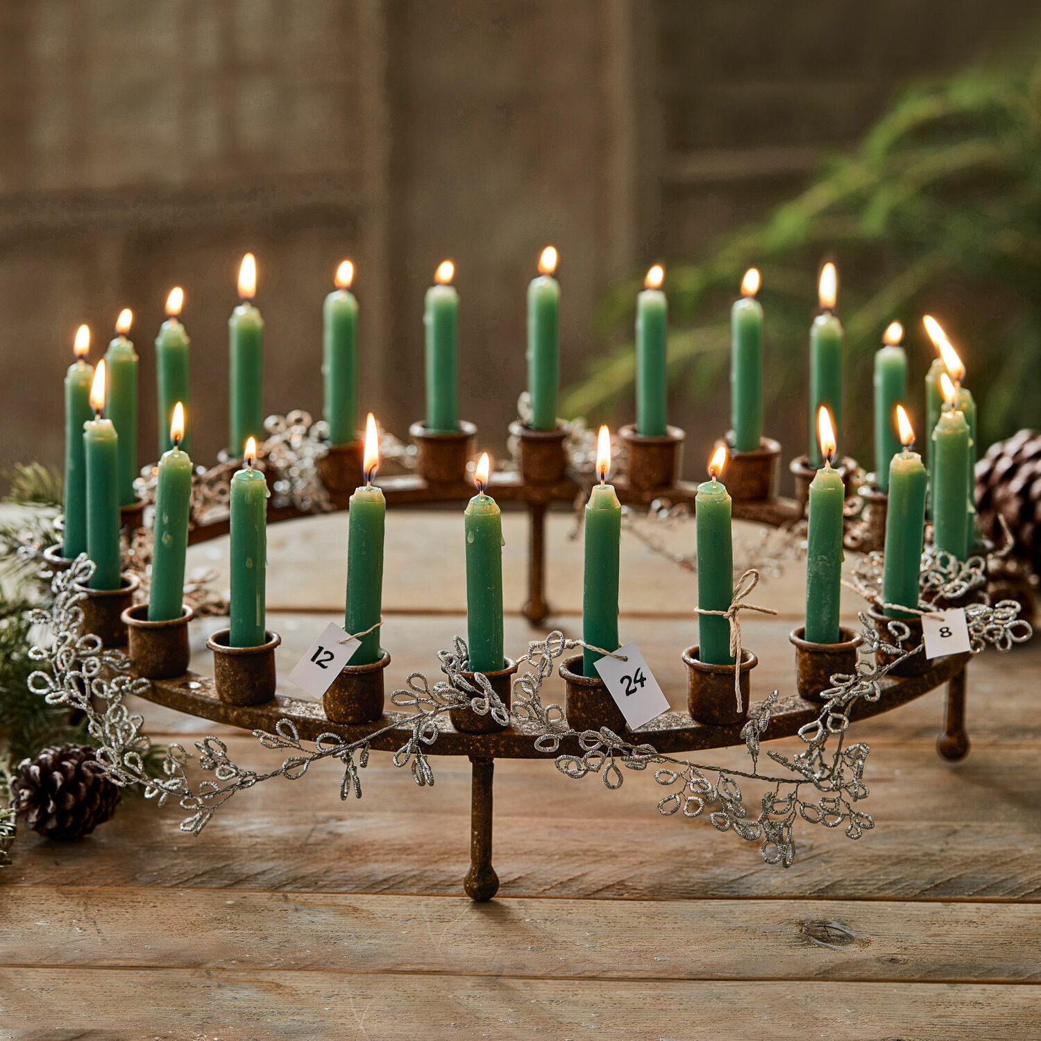 Metalen adventskrans met groene kaarsen en decoratie op houten tafel