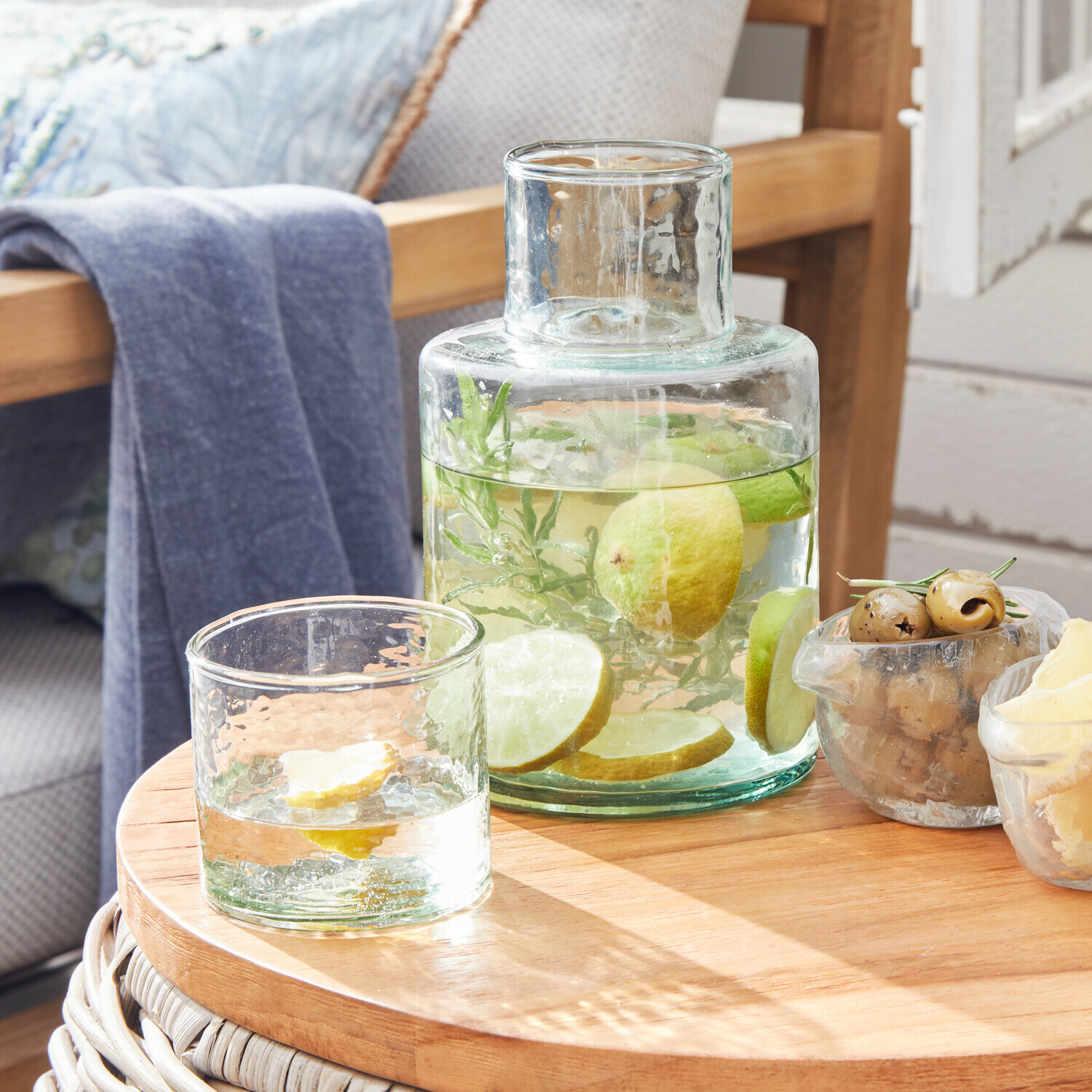 Glazen karaf en glas met water en citroenschijfjes op houten tafel voor interieurdecoratie