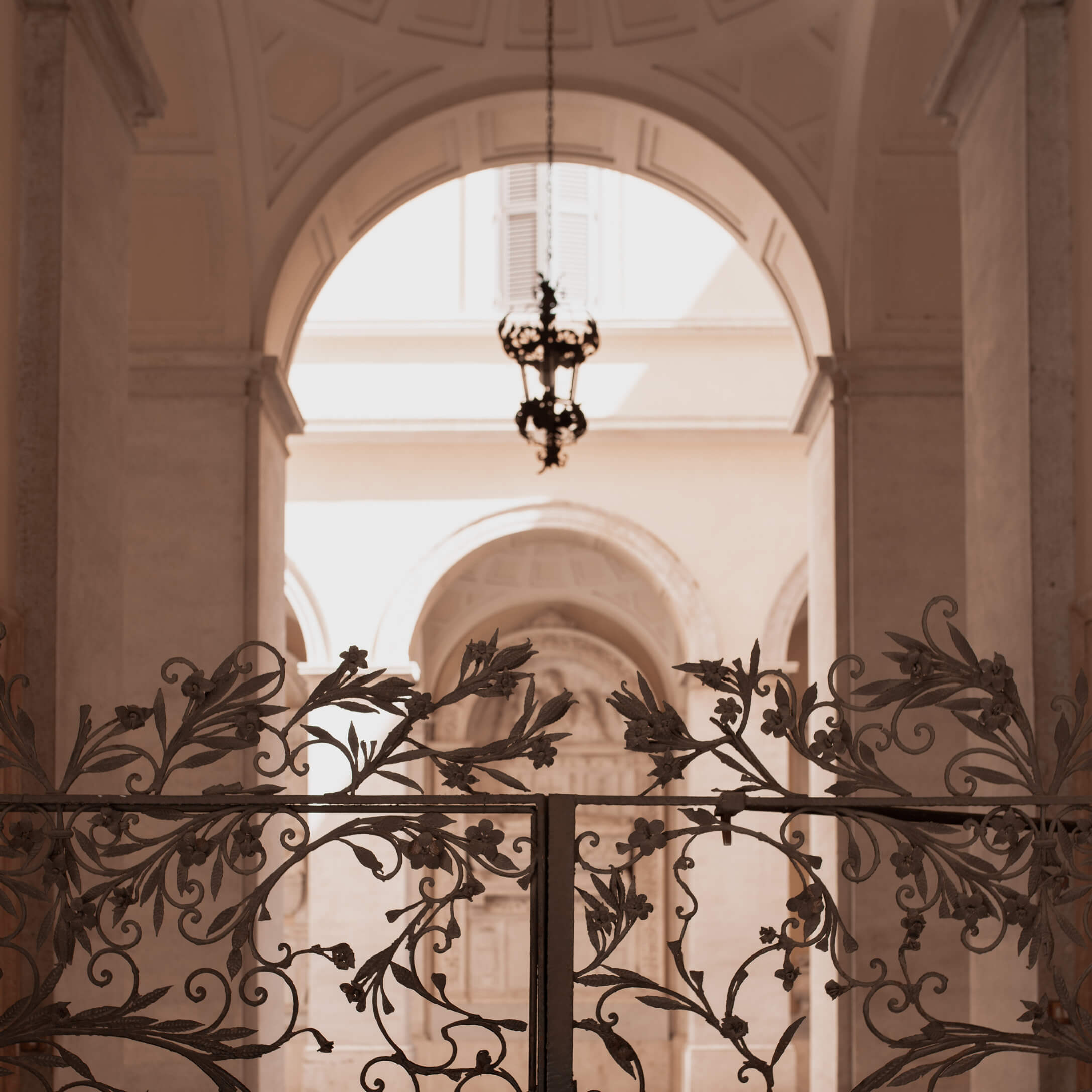 Smeedijzeren sierpoort met bloemmotief voor lichte boog en hangende lamp