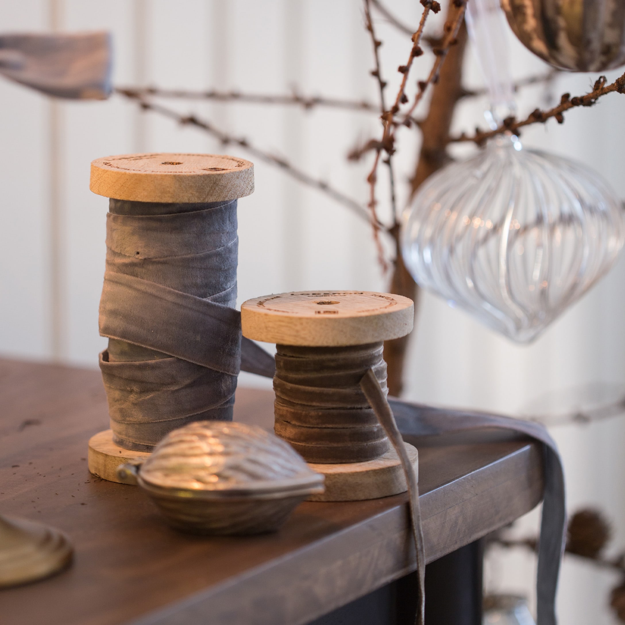 Houten spoelen met grijs en bruin fluwelen lint op houten tafel met kerstdecoratie