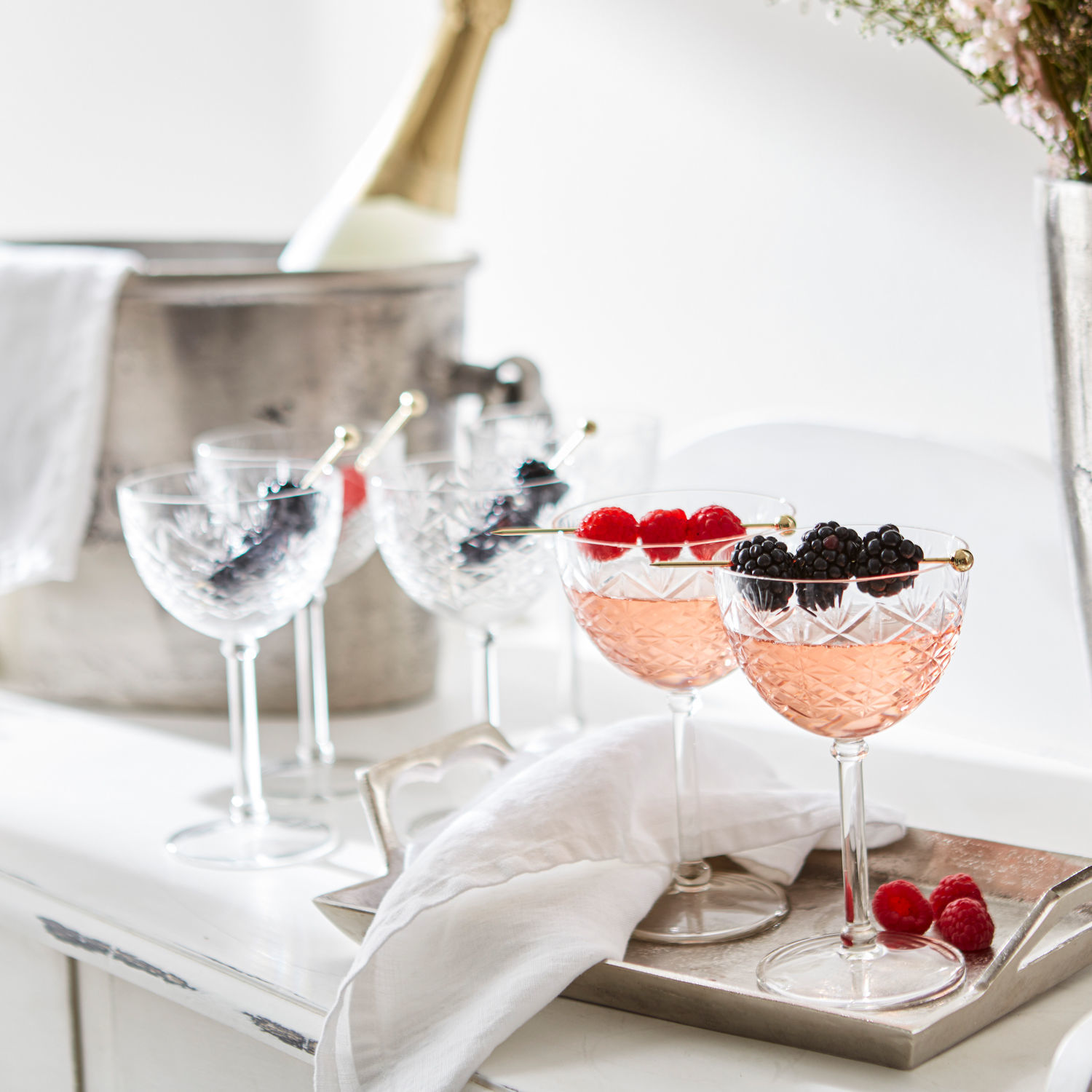 Kristallen cocktailglazen met frambozen en bramen op een zilverkleurige serveerschaal