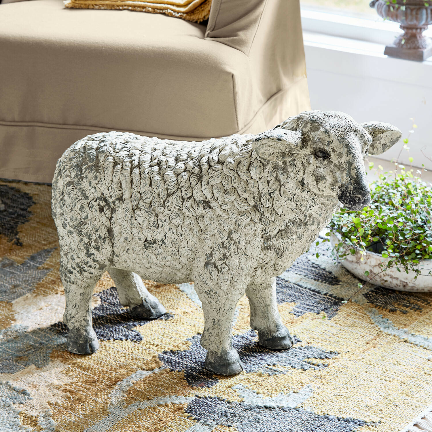 Beeld van een schaap van grijs steen op een vloerkleed, natuurlijke woondecoratie