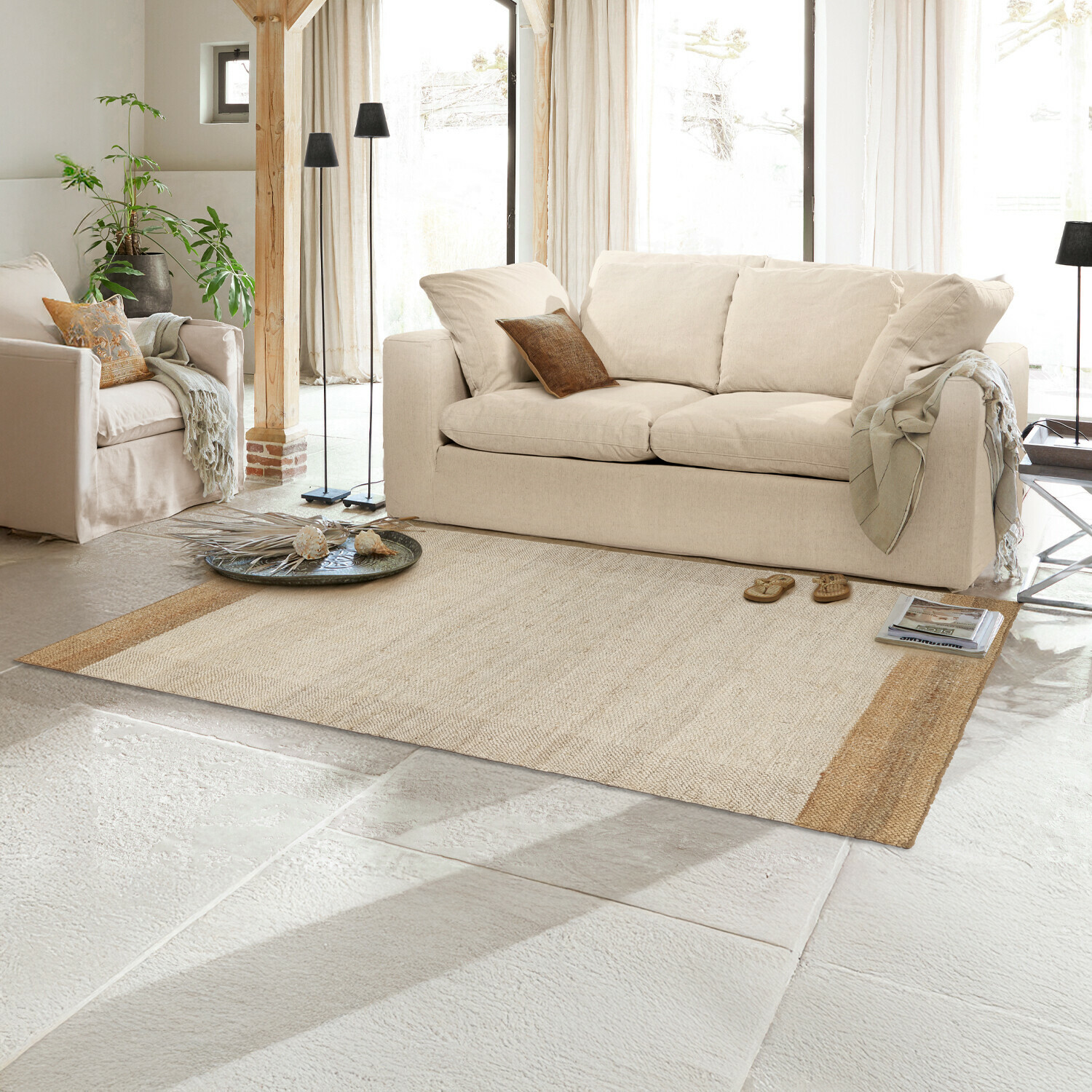 Beige vloerkleed van natuurlijke vezels in lichte woonkamer met crèmekleurige bank en decoratie