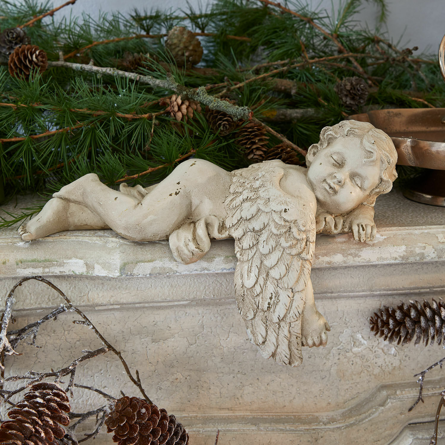 Decoratieve engel Deronza Beeldje van een crèmekleurige betonnen engel op schoorsteenmantel met dennentakken en dennenappels, kerstdecoratie