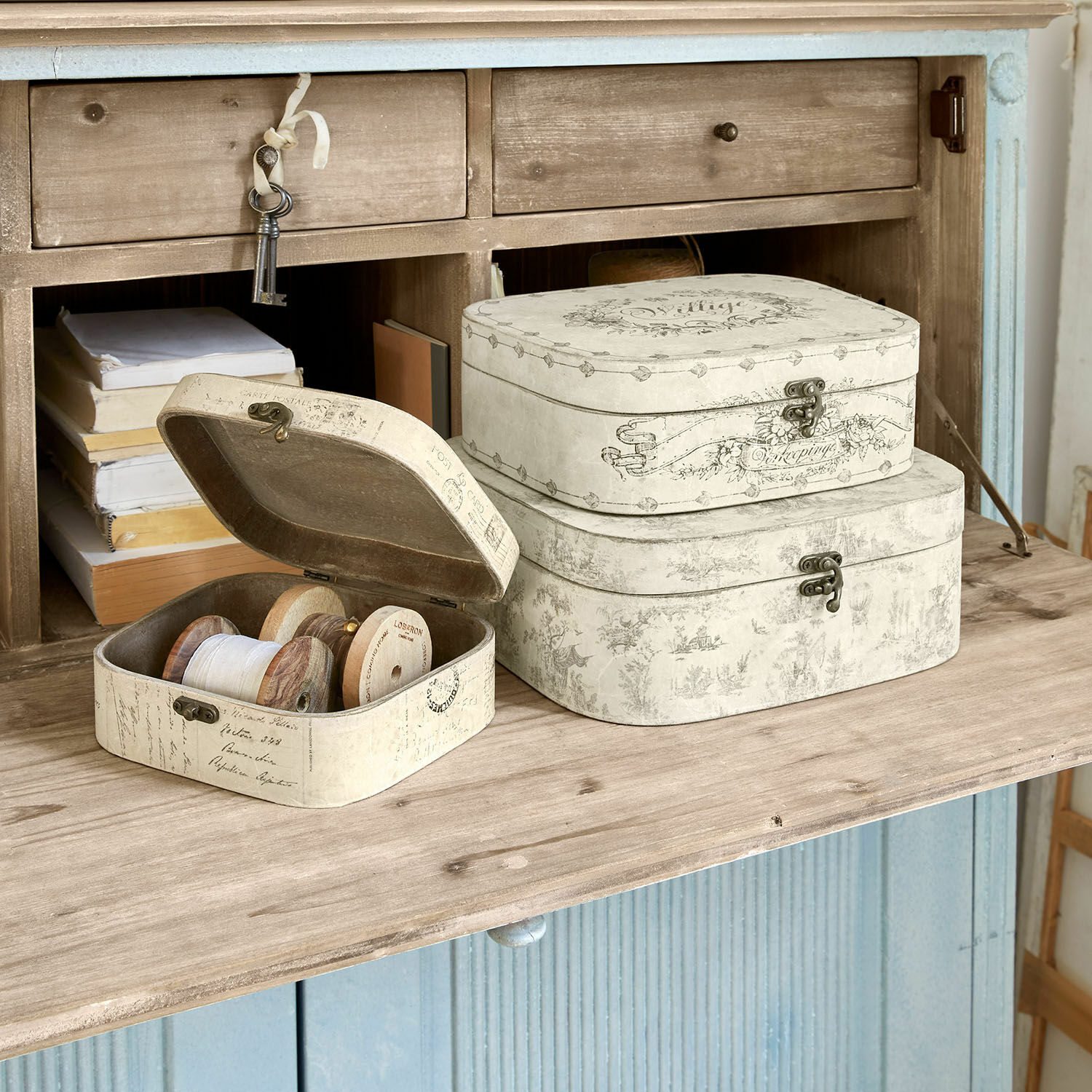 Set van drie crèmekleurige decoratieve dozen met metalen sluitingen op houten blad